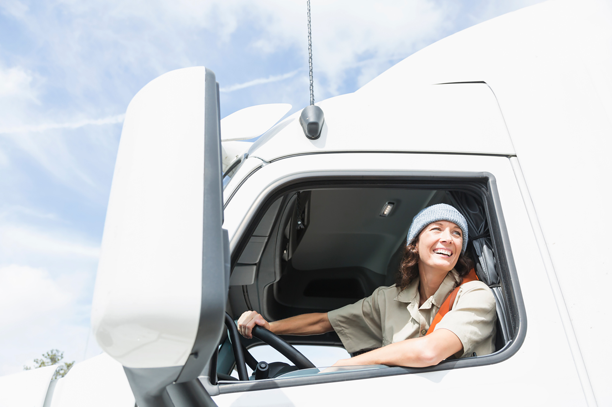 A female truck driver smiling outside the semi truck.